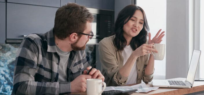 Man Looking at His Partner Talking While Holding a Cup of Coffee