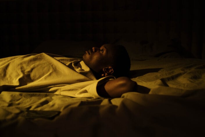 A man lying on his bed while thinking