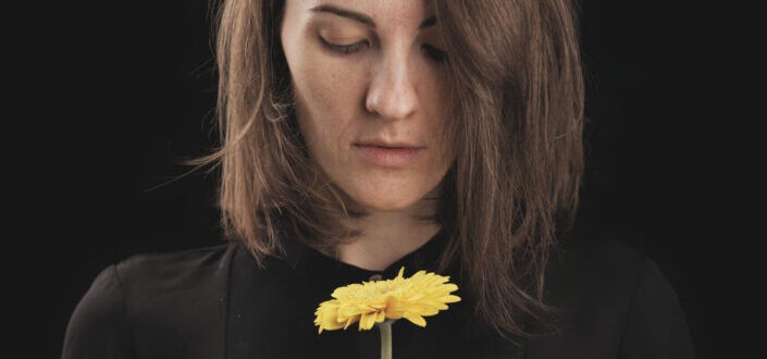 Woman in Black Top Holding a Yellow Flower