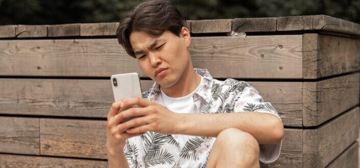 Frowning Man Browsing Smartphone in Countryside