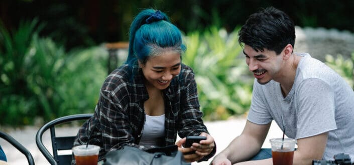 Cheerful Couple Browsing Smartphone in Cafe