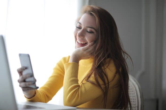 Cheerful Student Using Smartphone While Working