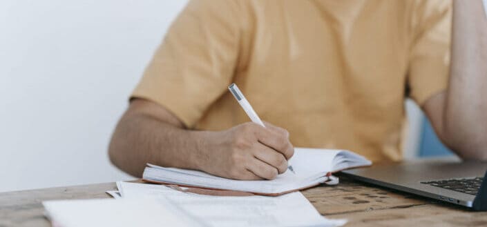 Man Writing on His Notebook