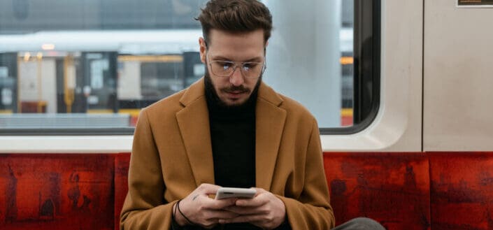 Man Sitting on a Train While Texting