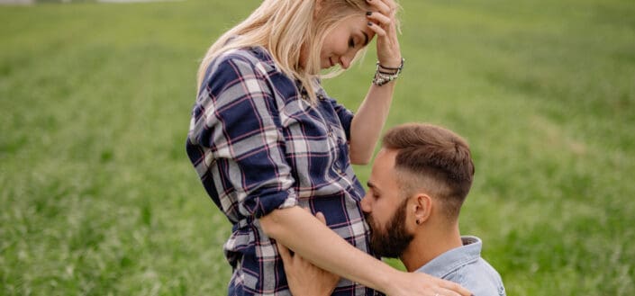 Man Kneeling and Kissing Her Pregnant Belly