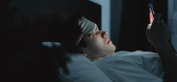 Man Lying on Bed Using a Cellphone