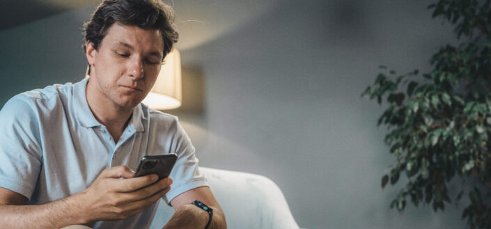 Man Texting While Sitting on a Sofa