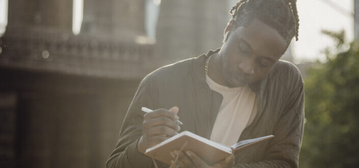 Man Taking Notes Against a Bridge