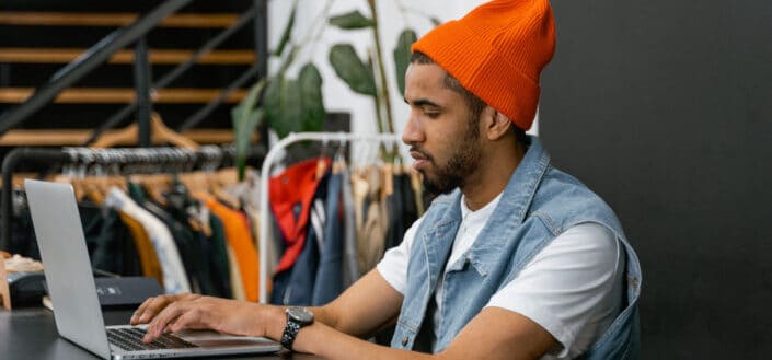 Man in Orange Beanie Using a Laptop