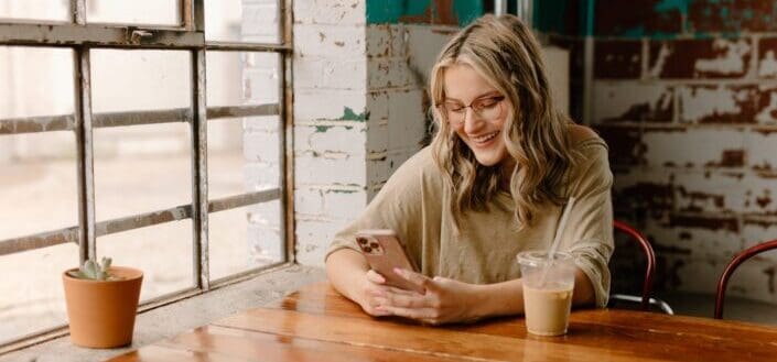 Woman Smiling at Phone in a Cafe