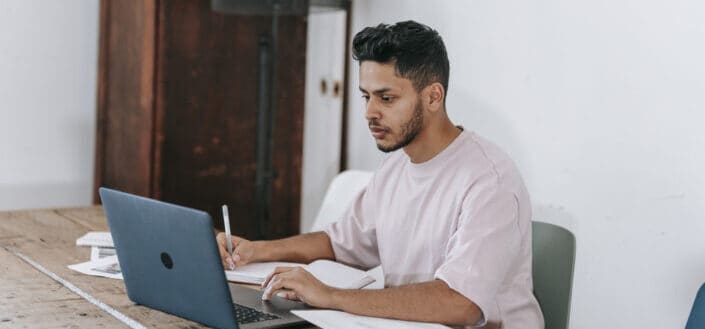 Young Man Working on Laptop and Writing