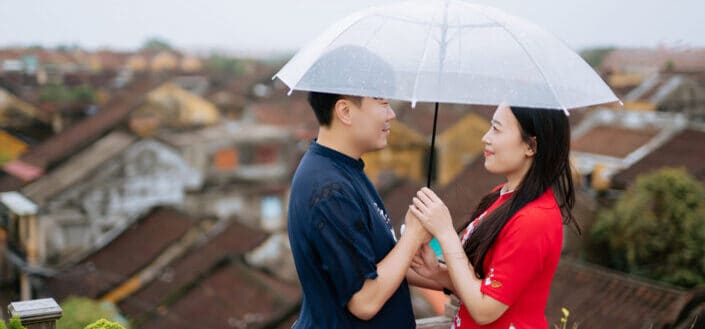 A couple holding an umbrella together
