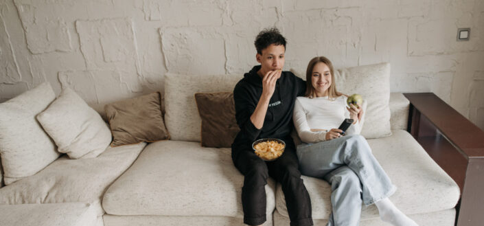 couple sitting on couch while eating snacks