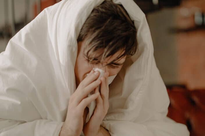 A sick man wiping his nose with tissue