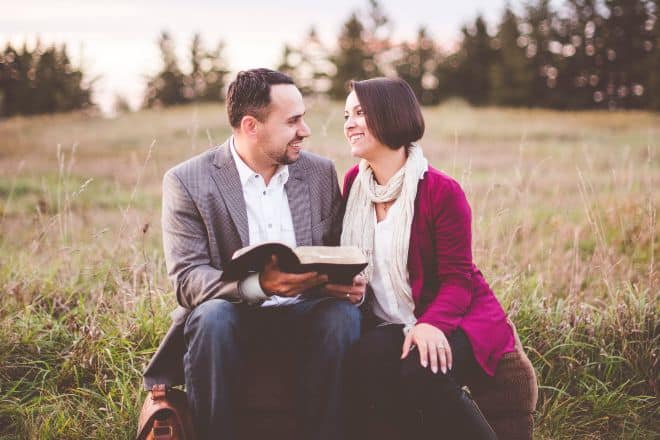 couple sitting on grass while reading book - Christian Pick Up Lines