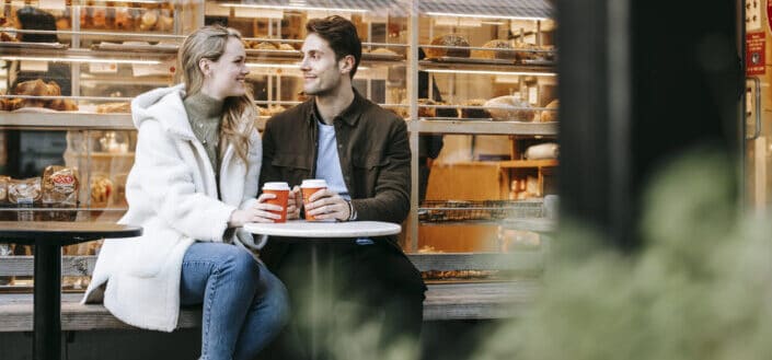 Happy couple having hot tea in cozy cafe