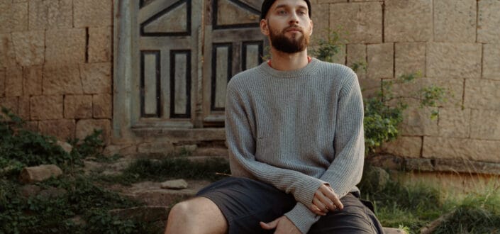 Man in gray sweater sitting on rocks