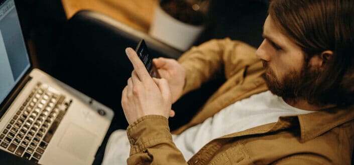 Man Using His Smartphone And Laptop