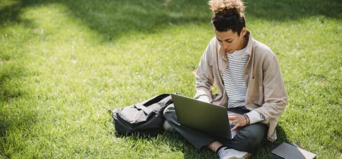 Student Typing on Laptop Sitting on Grass