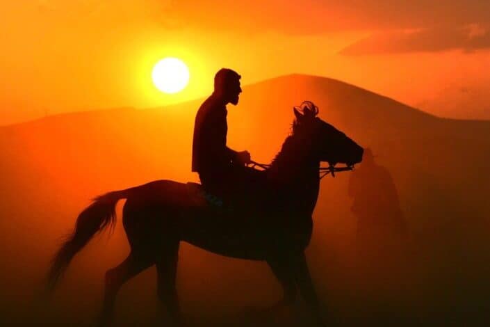 man riding horse at sunset