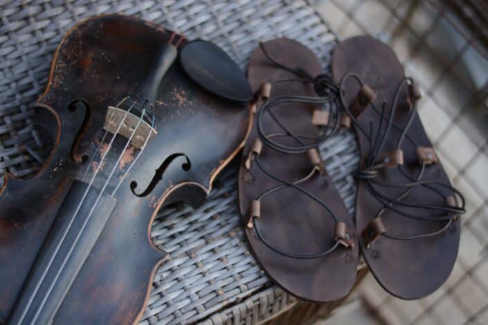 pair of rustic sandals beside a violin