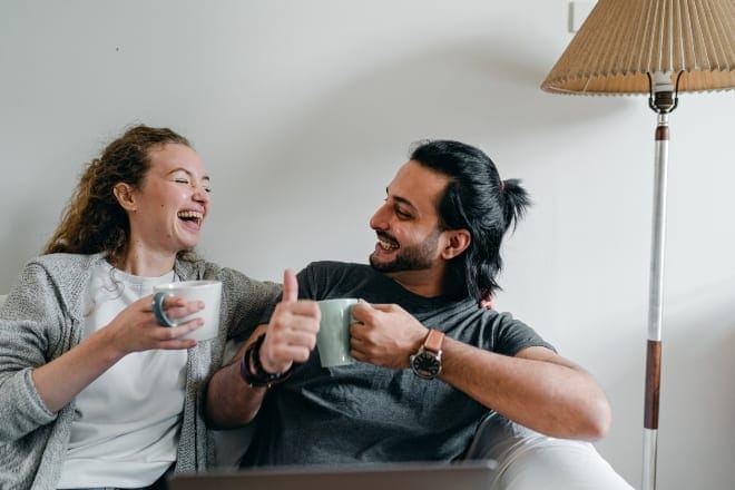 two people laughing together while drinking