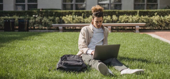 guy sitting on grass with laptop in front of him