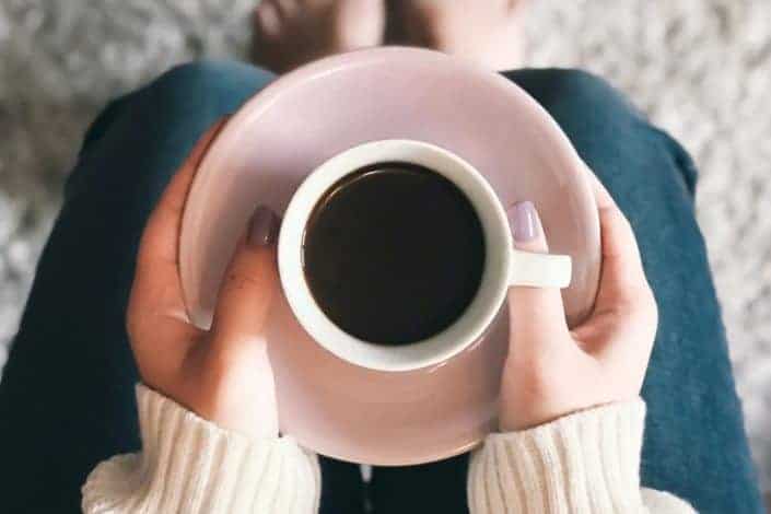 mug placed on coaster held by woman