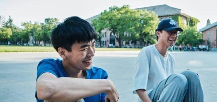 Two guys sitting along the highway, laughing