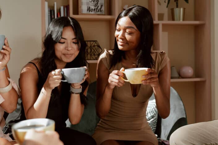 Two women smiling while drinking from mugs