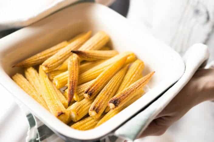 person holding bowl with yellow corns