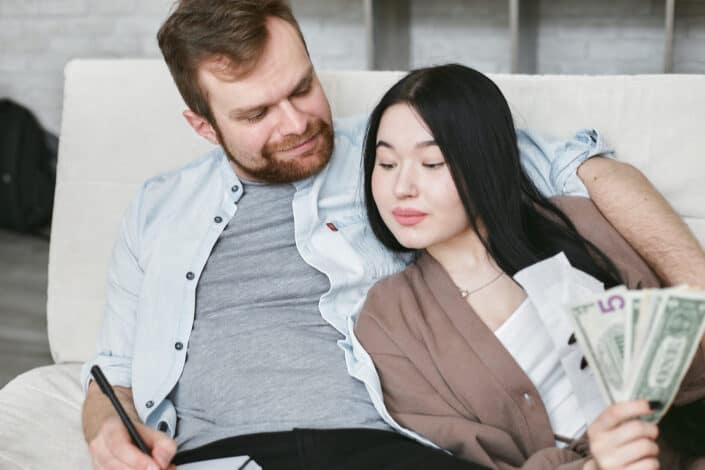 Couple Sitting Together on the Sofa Counting Money