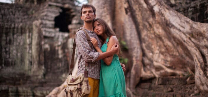 Couple hugging each other while standing beside an old tree