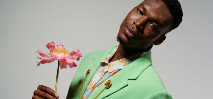 A man in green suit holding a flower