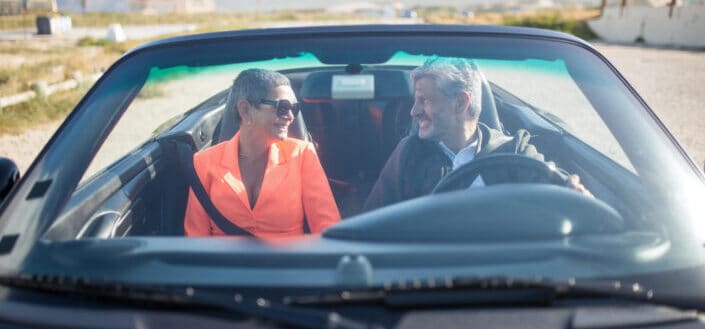 An elderly couple riding a cabriolet car