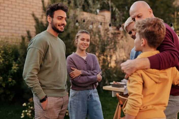 four people smiling and looking at a kid 