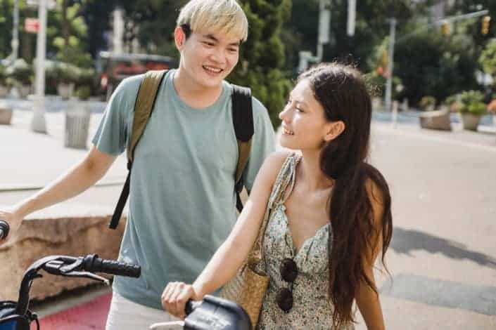 man and woman standing closely while holding bicycles