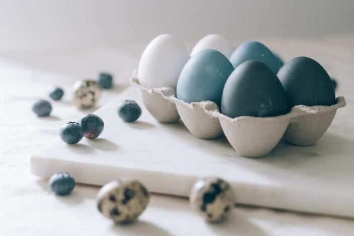 Blue and white eggs in a carton