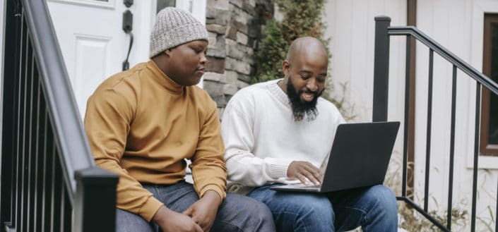 Cheerful black businessman browsing laptop with son