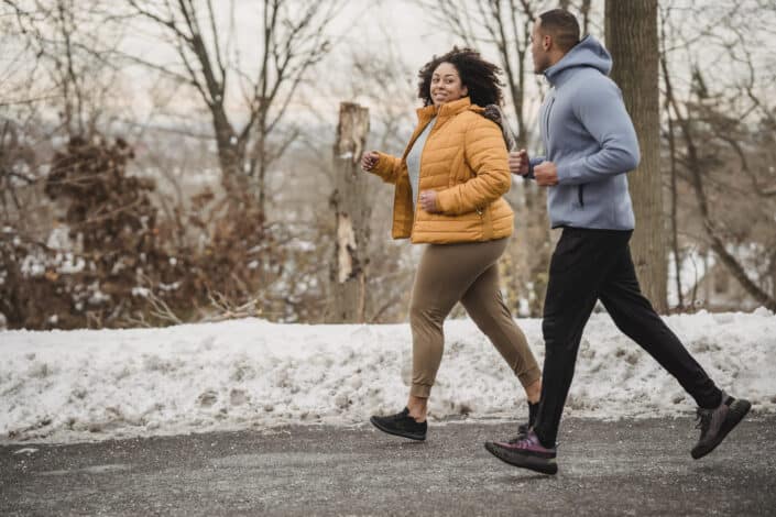 Man and Woman Jogging in Snowy Park