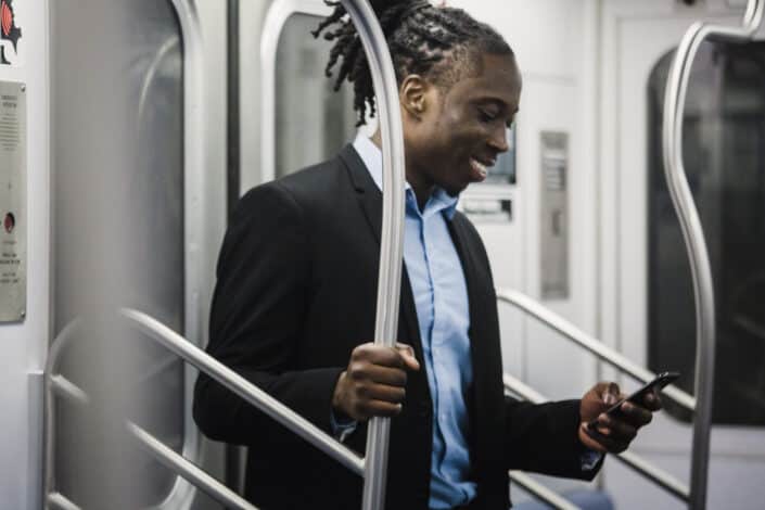 man smiling while using phone in train