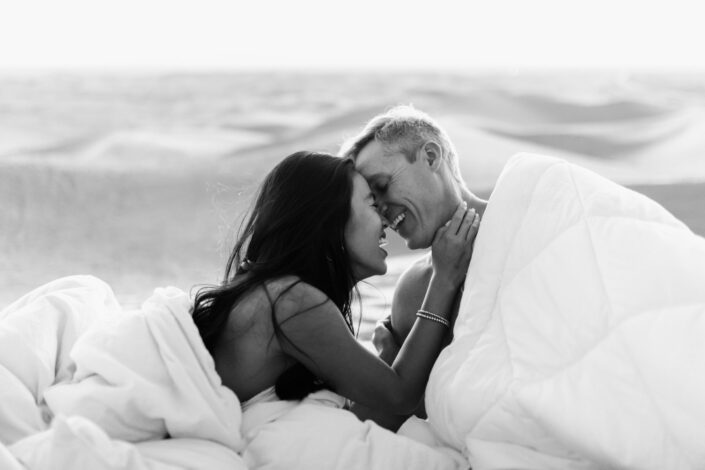 Sweet couple wrapped in a white comforter