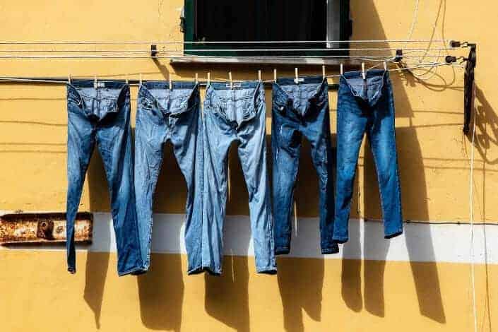 Five jeans hanged on a cable to dry.