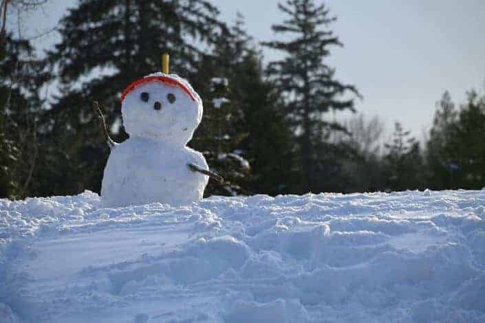 A snowman wearing a red sun visor.