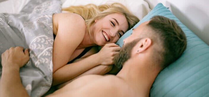 Couple giggling while lying in bed