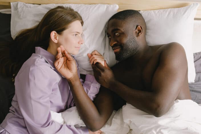 Couple lying on bed looking face to face