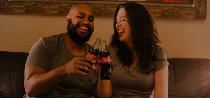 couple toasting a bottle of coca-cola