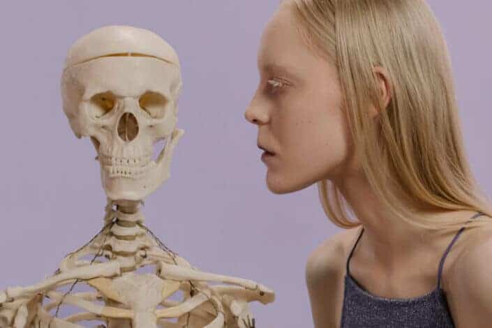 woman looking seriously at human skeleton