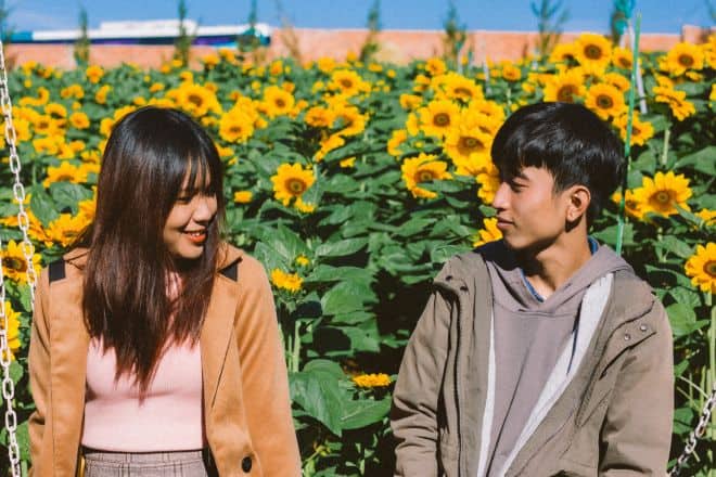 Couple Sitting Beside Sunflower Field - How Do You Know if a Guy Likes You