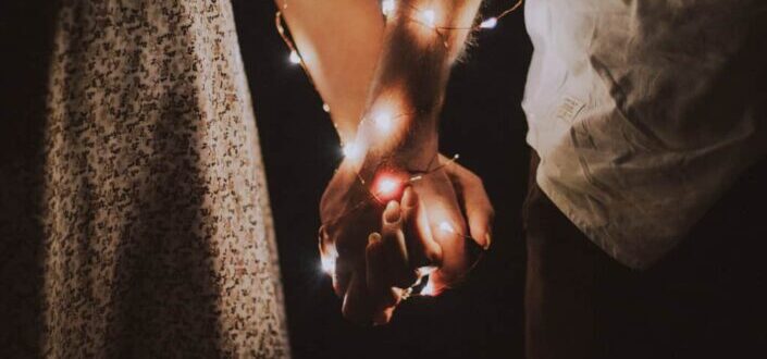 couple holding hands with lights